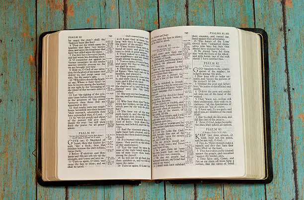 The holy Bible opened to the book of Psalm on a wooden plank rustic background