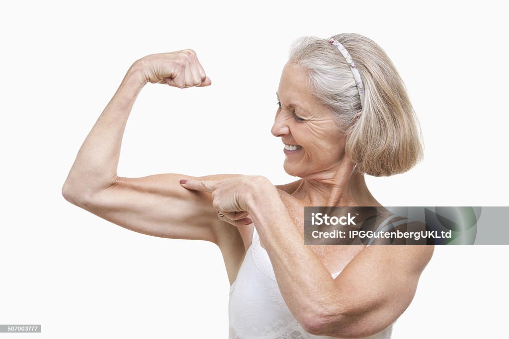 Senior woman studio portrait Senior woman flexing muscles against white background Senior Adult Stock Photo