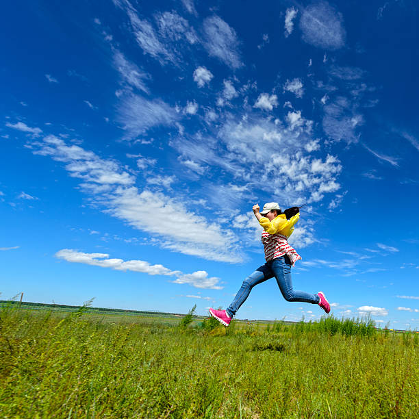 Happy girl jumping against the background of blue sky and clouds.