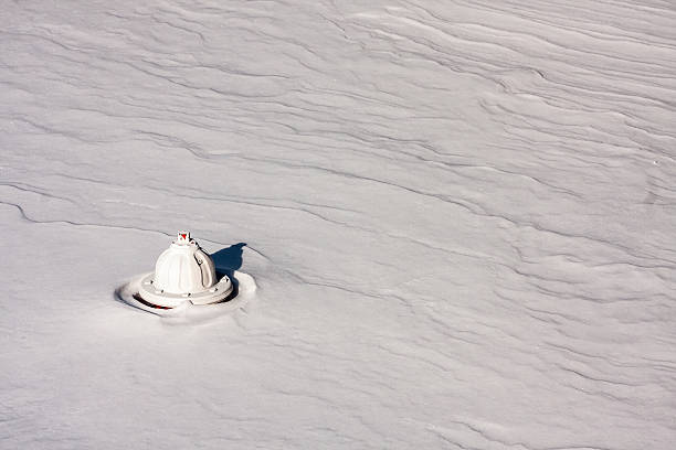fire hydrant sticking above a windblown field of snow, lower left corner