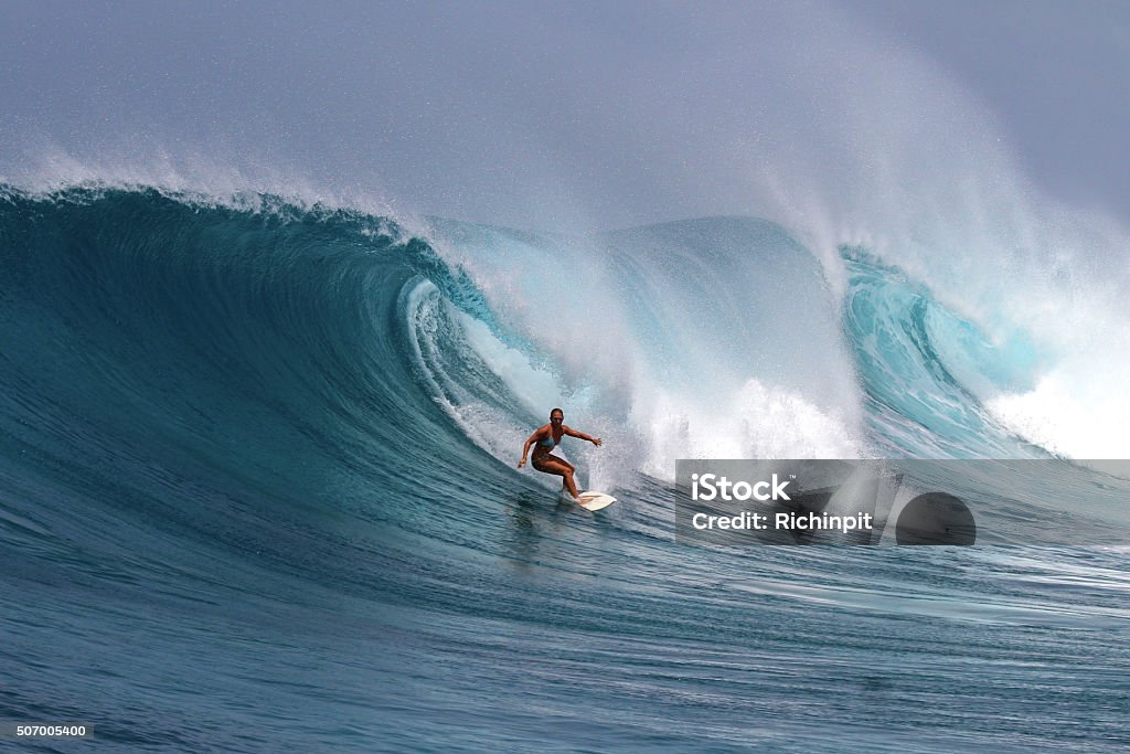 Brave girl surfs a big powerful wave A courageous girl surfs a big powerful wave in a tropical climate Surfing Stock Photo