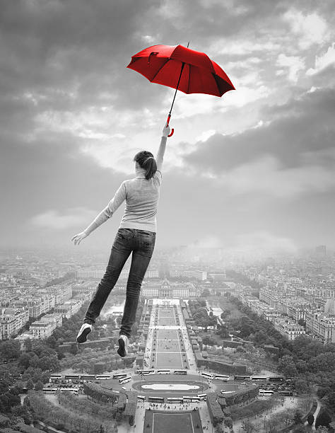 istock Young woman  with red umbrella flying over Paris 507006013