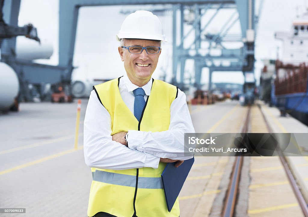 Let us help put your cargo safely on its way Portrait of a dock worker standing at the harbor amidst shipping industry activity Males Stock Photo