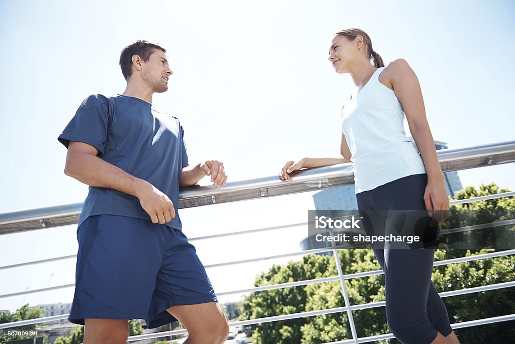 Taking a break at the halfway mark Low angle shot of two young people having a conversation while taking a break from their exercise outdoors 20-29 Years Stock Photo