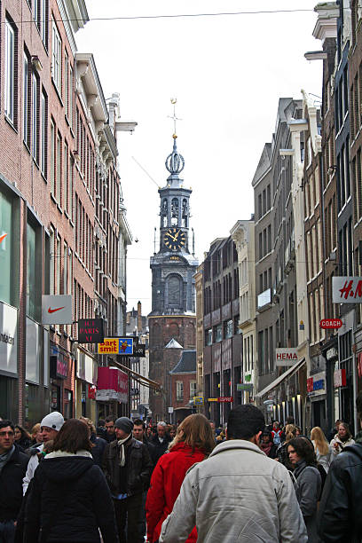 Amsterdam, Netherlands - March 28, 2009: Crowds move along Kalverstraat's pedestrian mall with the Munttoren (aka Coin Tower or Munt) at the end of the street.