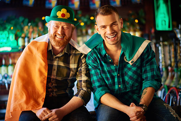 Cheerful Irishmen wrapped with Irish flag in bar