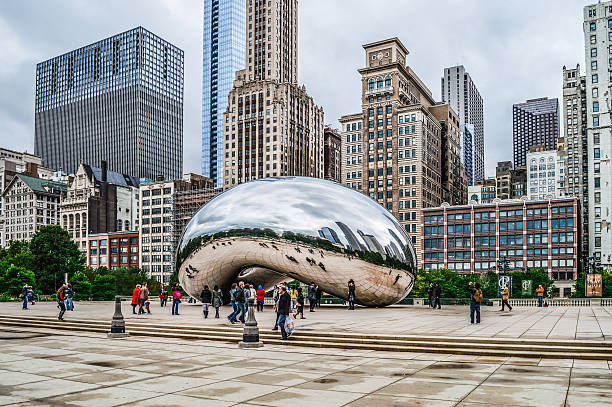 Chicago Bean in Millennium Park with Reflection of Skyscrapers Chicago, USA - October 17, 2013: People enjoying the view of the of the skyscrapers in the reflection of the Chicago Cloud Gate in Millennium Park. millennium park chicago stock pictures, royalty-free photos & images