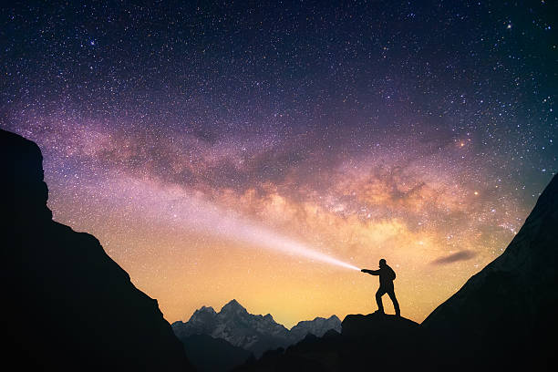 Skywalker Silhouette of the man standing against the Milky Way in the mountains with a flashlight in his hands. Nepal, Everest region, view of the mount Thamserku (6,608 m) from Thame village (3,750 m). lanterns at night stock pictures, royalty-free photos & images