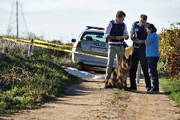 Shot of two policemen interviewing a woman at a crimescene