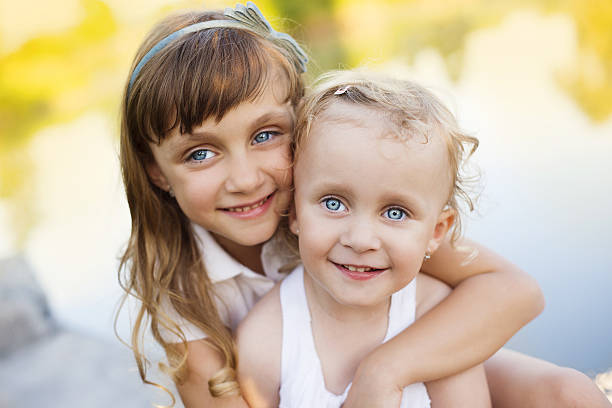 Caucasian little girls arm around posing together in a park