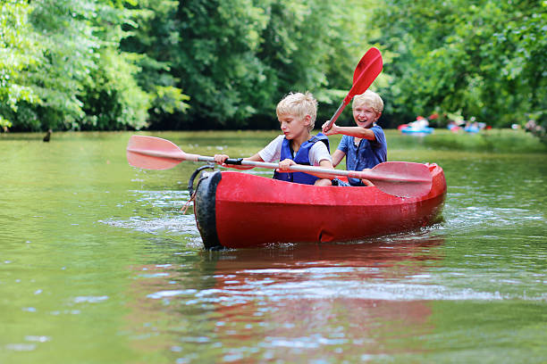 2 つの幸せな男の子カヤックで川をお楽しみいただけます。 - family kayaking kayak canoeing ストックフォトと画像
