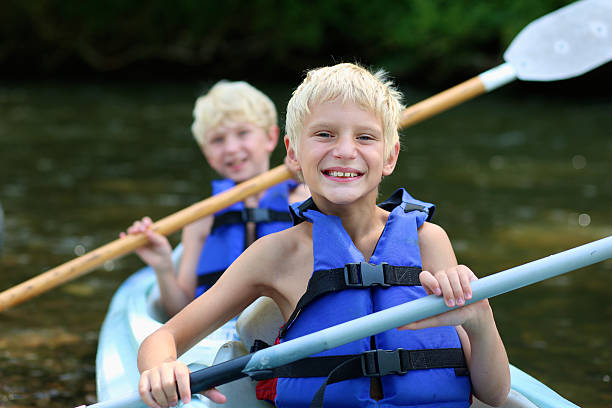 dwa szczęśliwy chłopcy się kajak na rzece - summer camp child teenager kayak zdjęcia i obrazy z banku zdjęć