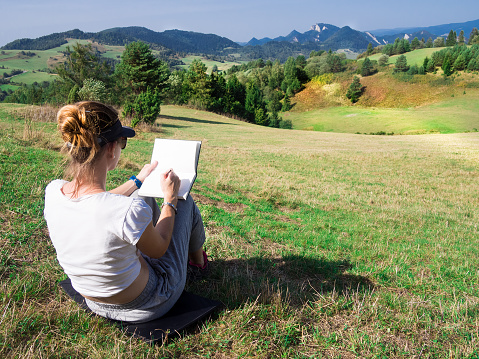 Woman artist working outdoors on hillside