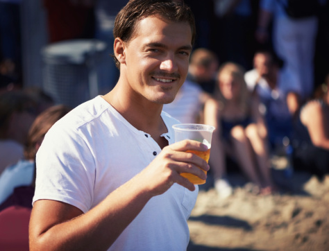Portrait of a young man enjoying a cool, crisp beer at a music festival