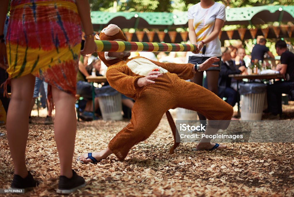 Monkeying around A guy dressed in a monkey costume doing the limbo dance at a music festival Humor Stock Photo