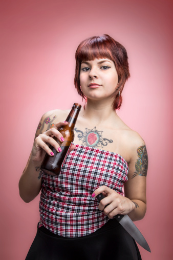 Young attractive woman with heart shaped tattoo holding beer and knife