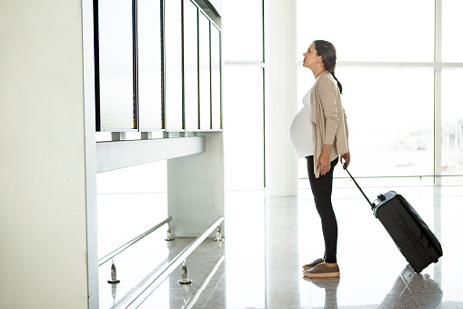 Pregnant woman looking at departure monitor