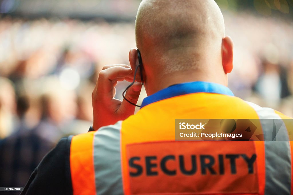 He's there for your protection Rear view of a security guard listening to his headset Security Staff Stock Photo