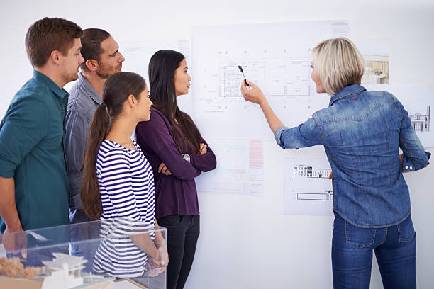 Familiarising themselves with every aspect of the plans Cropped shot of a group of architects discussing plans familiarising stock pictures, royalty-free photos & images