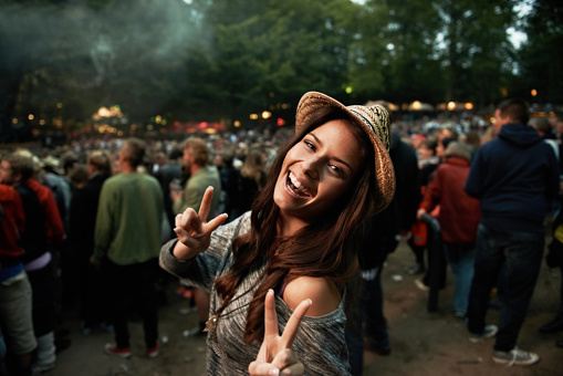 A pretty young woman showing a peace sign at an outdoor music festival