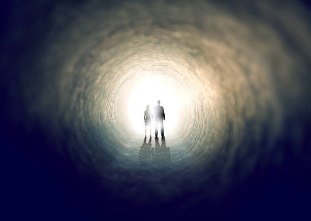 Into the light... A shot of two people finding an exit from a dark tunnel - ALL design on this image is created from scratch by Yuri Arcurs'  team of professionals for this particular photo shoot light at the end of the tunnel photos stock pictures, royalty-free photos & images