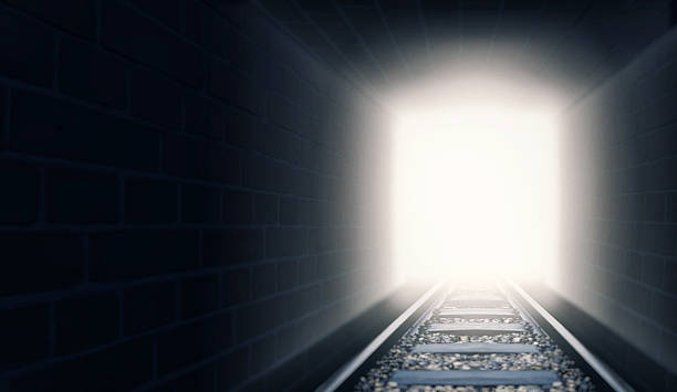 Out of the darkness and into the light A shot of train tracks coming out of a dark tunnel - ALL design on this image is created from scratch by Yuri Arcurs'  team of professionals for this particular photo shoot light at the end of the tunnel stock pictures, royalty-free photos & images