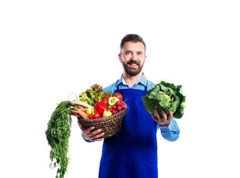 Young handsome gardener in blue apron. Studio shot on white background