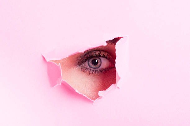 istock Female eye with make-up looking thru cut out cardboard 507070338