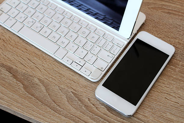 White smartphone and white tablet with keyboard stock photo