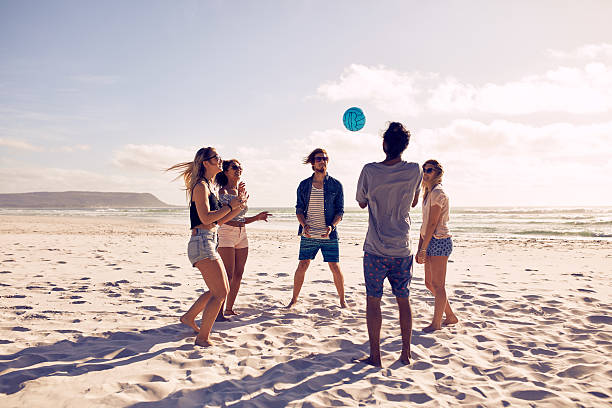 jovens a brincar com a bola na praia - volleyball beach volleyball beach sport imagens e fotografias de stock