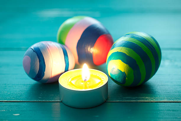 Colorful easter eggs and candle on turquoise wooden table. This file is cleaned and retouched.