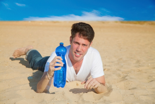 Caucasian man with a bottle of fresh water in desert