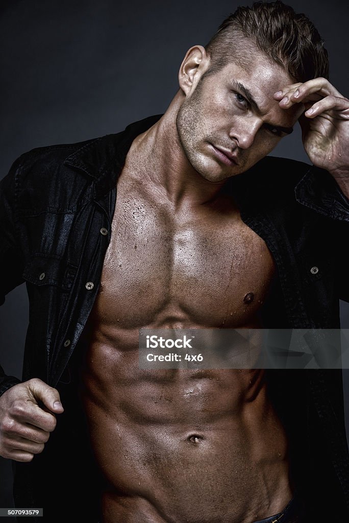 Muscular man standing in front of black background Muscular man standing in front of black backgroundhttp://www.twodozendesign.info/i/1.png Men Stock Photo