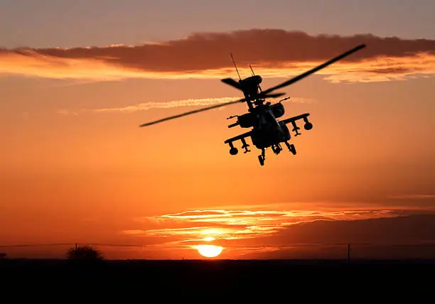  AH-64 Apache rises up  to ambush its target under a sunset sky.