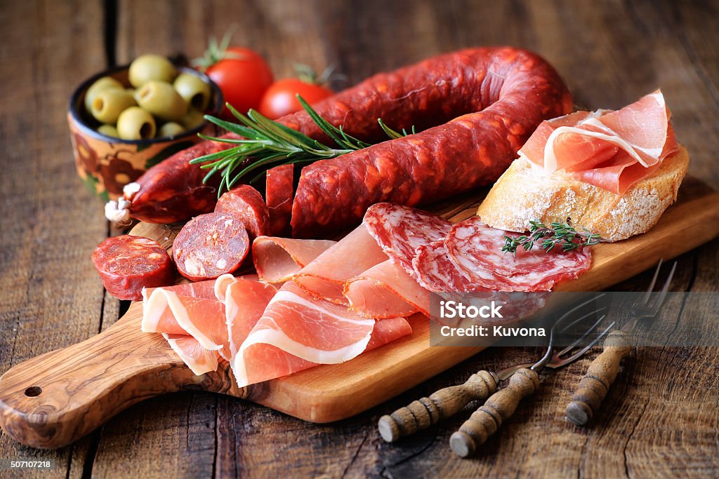 Spanish meat tapas Cured meat platter of traditional Spanish tapas - chorizo, salsichon, jamon serrano, lomo - erved on wooden board with olives and bread Processed Meat Stock Photo