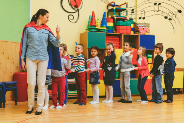 grupa dzieci bawiące się z ich nauczyciel w chodzić do przedszkola - school activities zdjęcia i obrazy z banku zdjęć