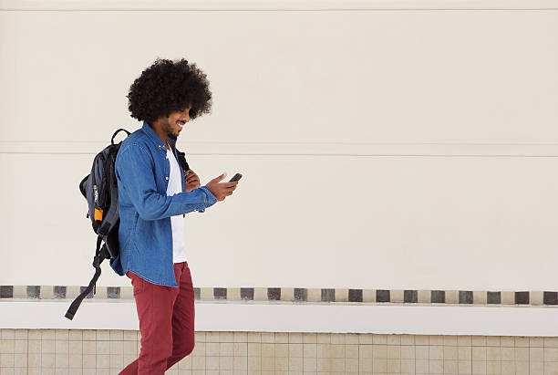 istock Male student walking with bag and mobile phone 507108558