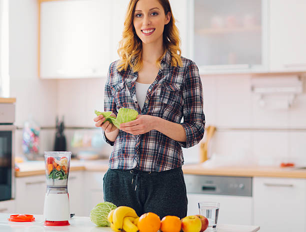 Young Smiling Woman making smoothie.
