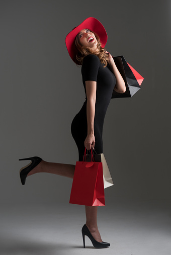 Glamorous fashion woman shopping  and holding bags while wearing a hat in the studio