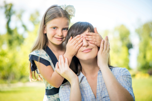 Portrait of a smiling girl covering her mother eyes