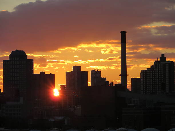 il sole al tramonto tra edificio con forte effetto raggio di sole - sundow foto e immagini stock