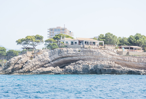 Calvia, Balearic islands, Spain - July 19, 2014: Coastal geomorphology, folded cliff with a building, on a sunny summer morning in July.