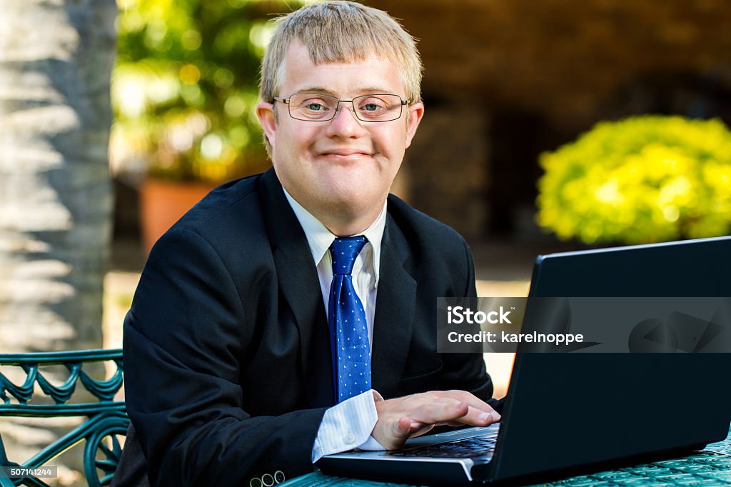 Joven empresario trabaja con la computadora portátil para personas con discapacidades. - Foto de stock de Síndrome de Down libre de derechos