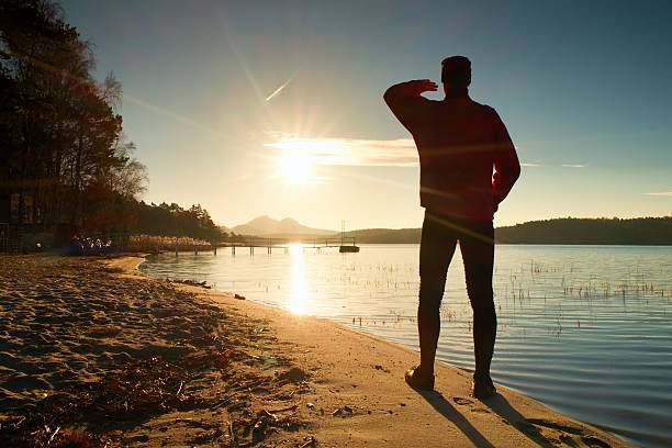 istock . Slim sportsman on beach shadowing eyes . 507147118
