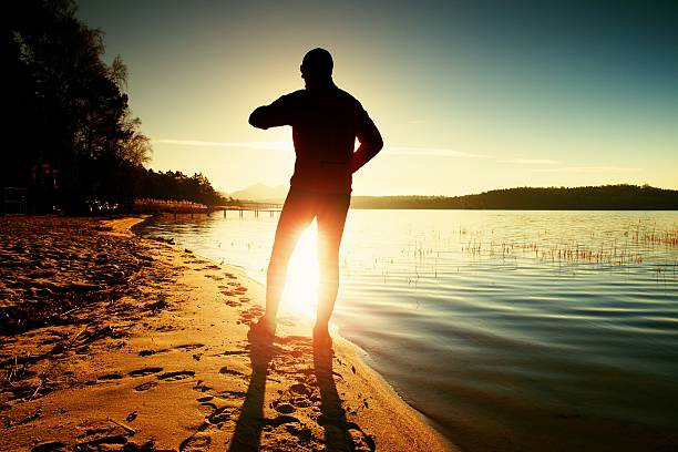 istock Man check time and do exercising on beach. Calm water 507147312