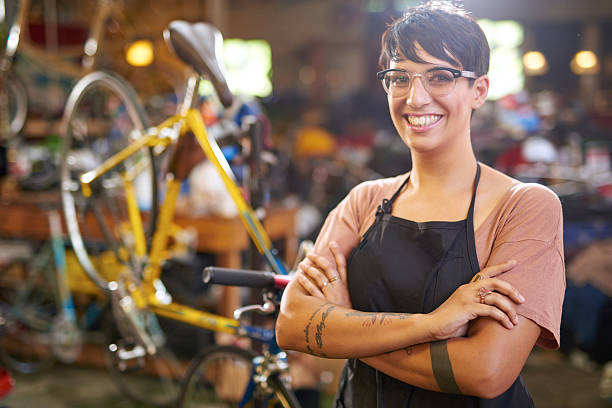 Female technician in her bicycle repair shop Female young  technician looking at the camera in her bicycle repair shop bicycle shop stock pictures, royalty-free photos & images