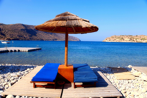 Two lounge chairs with sun umbrella on a beach, Crete, Greece