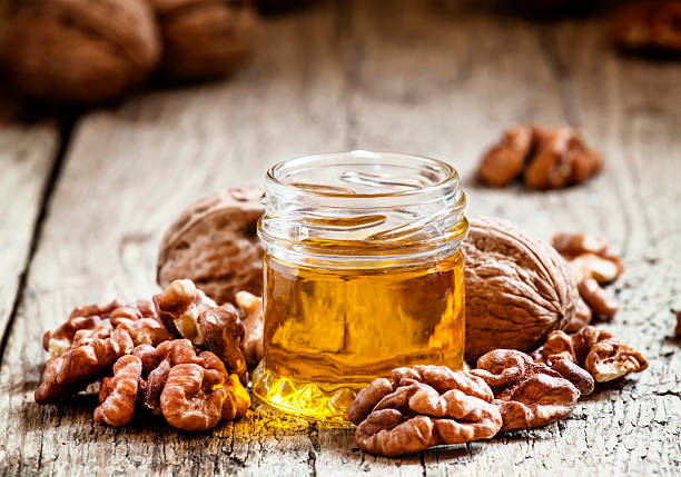 aceite de nueces en una pequeña de cristal y núcleos de - nuez fotografías e imágenes de stock