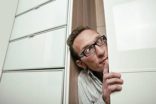 istock Frightened man peep out white wardrobe. Copy space right 507160017