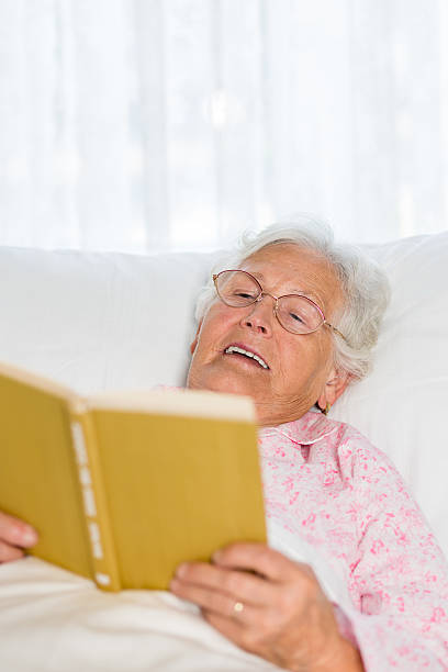 istock Senior woman in bed reading a book 507161617